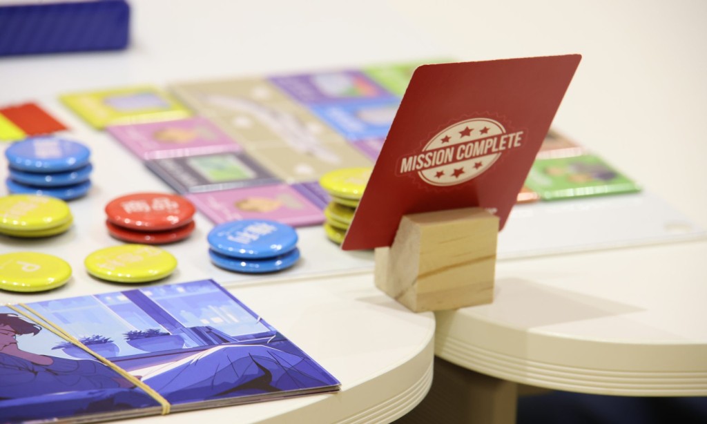 ビジネス教材のトークンと「MISSION COMPLETE」と書かれたカード、およびゲームボードのクローズアップ